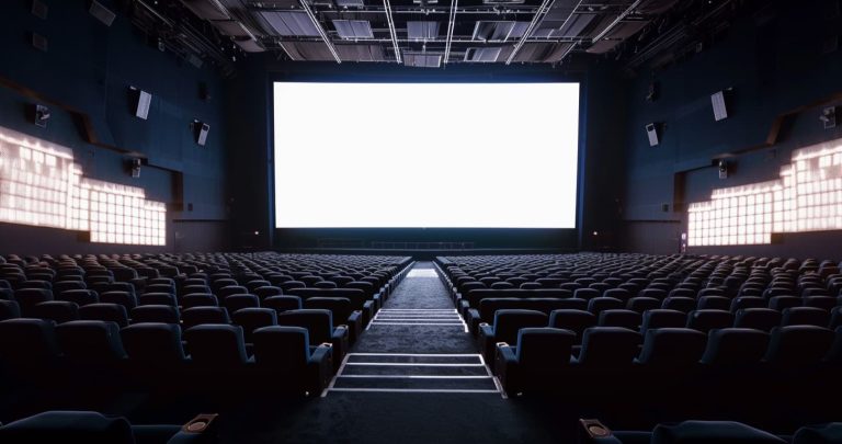 Empty cinema auditorium with a wide curved panoramic screen, ScreenX Explained